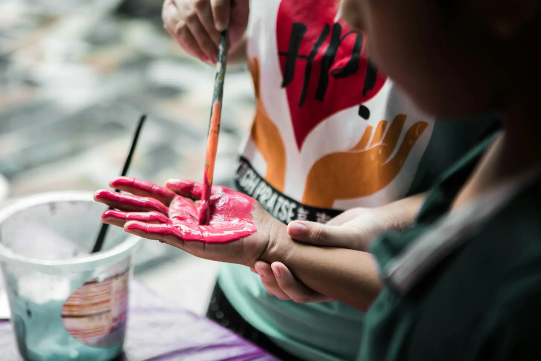 Un niño pintándose la palma de la mano con pintura rosada